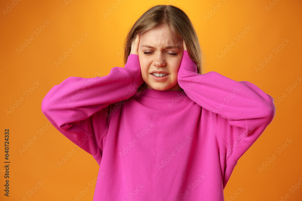 Teenage girl is touching her temples suffering headache on yellow background Teenage girl is touching her temples suffering headache on yellow background