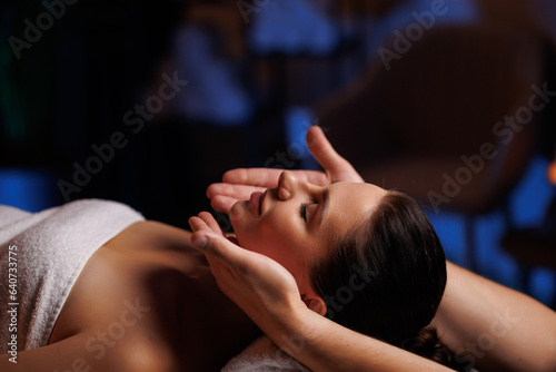 The hands of a masseuse make a manual massage of the head of a beautiful female client, antiaging procedure against wrinkles. The concept of scalp treatment and hair growth stimulation. Relax complex.
