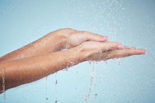 Cleaning, hands and water splash on woman in studio, blue background and healthcare mockup and washing for skincare. Model, closeup or hygiene with clean, soap or bubbles for protection from bacteria