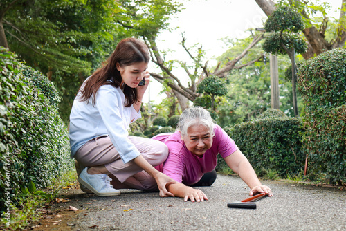 Asian woman calls an ambulance to help an elderly woman who has fallen in an accident on the road. The concept of health care for the elderly.