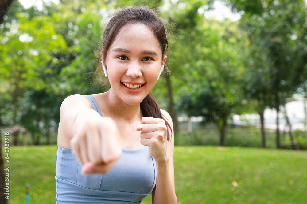 Portrait of beautiful Asian woman smiling happy exercising in the park in the morning She did boxing. sports concept