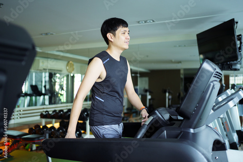 Active Asian sportsman making a cardio exercise by running on the treadmill machine in a fitness or gym, healthy sport man doing a cardio workout.
