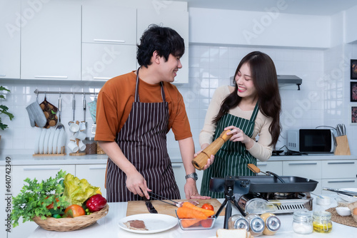 Happy portrait of loving young asian of having fun standing a cheerful preparing food and enjoy cook cooking with vegetables  meat  bread while standing on a kitchen Condo life or home