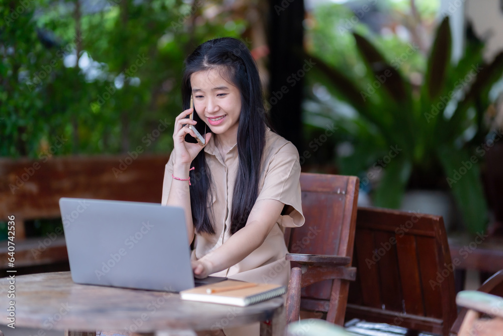 Happy of Young asian teen girl college student talking making using smartphone casual using laptop computer.Online education, elearning concept,freelance people businessfemale Happy of Young asian teen girl college student talking making using smartphone casual using laptop computer.Online education, elearning concept,freelance people businessfemale