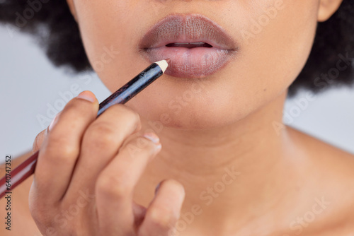 Makeup, cosmetics and lips of woman with pencil in studio for wellness, skincare product and beauty. Salon, aesthetic and face zoom of person with lipstick or lip liner for glamour, makeover and glow © LuneVA/peopleimages.com