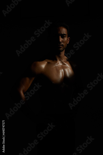 Topless, muscle and portrait man in dark background for fitness inspiration, beauty aesthetic or strong body. Shadow aesthetic, topless male model or body builder in creative studio with art lighting