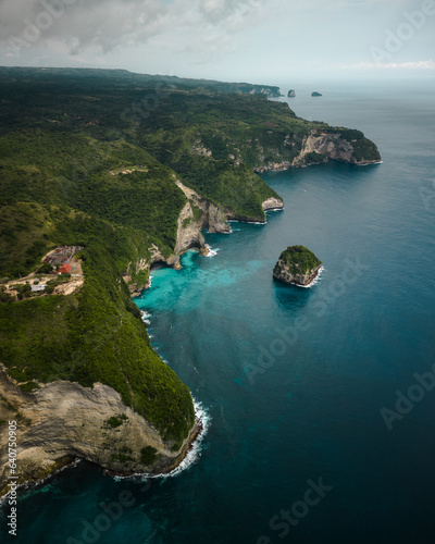 Nusa Penida's Coastal Majesty: Aerial Perspective of Bali's Oasis with Crystal Clear Waters, Pristine Coastline, and Enchanting Cliffs. Journey to Paradise in Indonesia's Top Vacation Destination