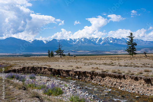 Beautiful mountain landscape, sunny morning, blue sky with clouds, snow-capped peaks and a river