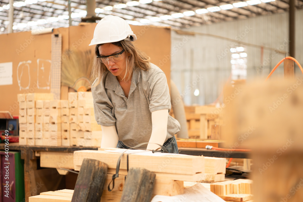 A carpenter works in a carpentry workshop. She collects the wood that passes through the wood angle grinder. A carpenter works in a carpentry workshop. She collects the wood that passes through the wood angle grinder.