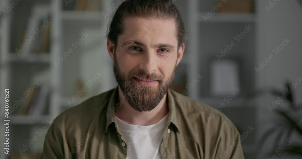 Portrait of smiling man with long hair and beard standing inside office. Portrait of smiling man with long hair and beard standing inside office.