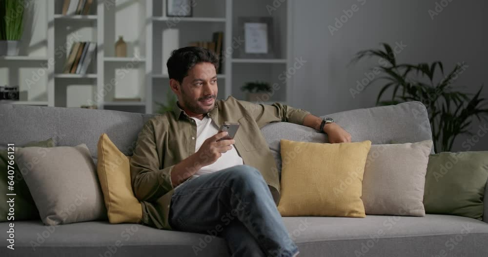 Man sitting on the sofa in office center and relaxing, using smartphone. Man sitting on the sofa in office center and relaxing, using smartphone.