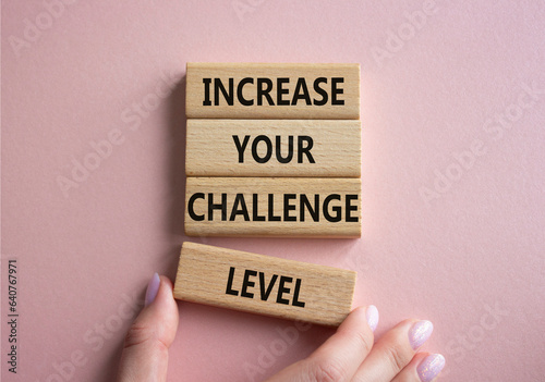 Challenge Level symbol. Concept word Increase your Challenge Level on wooden blocks. Beautiful pink background. Businessman hand. Business and Increase your Challenge Level concept. Copy space