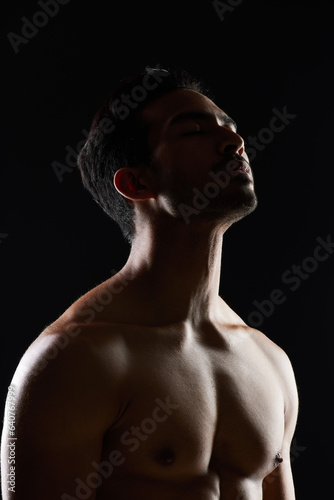 Bodybuilder man, muscle and shadow in studio with wellness, healthy body and black background. Young guy, fitness and silhouette in dark, thinking and strong with ideas, health and shirtless for art