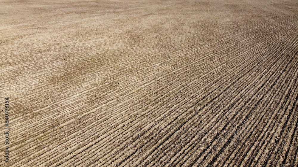 Plowed farm field aerial view, black soil as background.