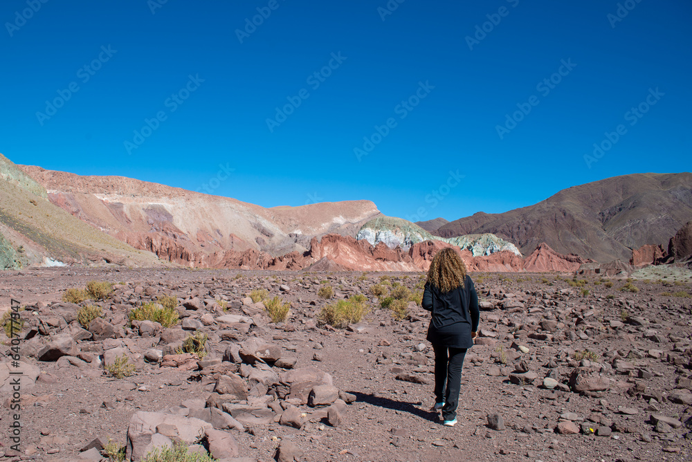 woman black dressed walking to the rocks of valle arcoiiris, antofagasta, atacama, chile