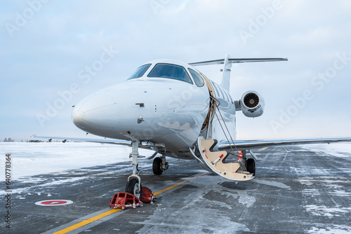 Fototapeta Naklejka Na Ścianę i Meble -  Modern white executive aircraft with an opened gangway door at the winter airport apron