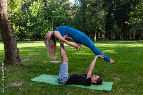 Boy and girl doing acro yoga outdoors in summer in public park