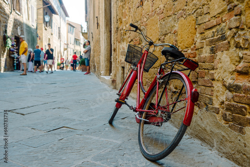 San Quirico d'Orcia, Tuscany: Red bicycle leaning against an old wall along the street