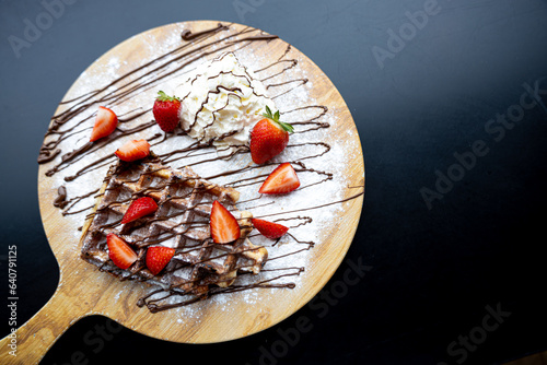 waffle with chocolate sauce on a platter with whipped cream top view