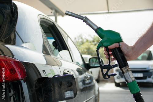 Closeup of the hand of a caucasian man holding up the petrol pump before refueling.