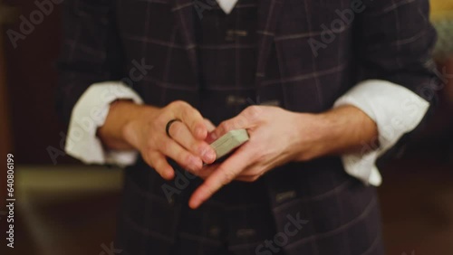 Magician illusionist with a deck of cards showing card tricks focus in front of wealthy rich guests on party event wedding celebration, juggler show, prestidigitator performance on stage