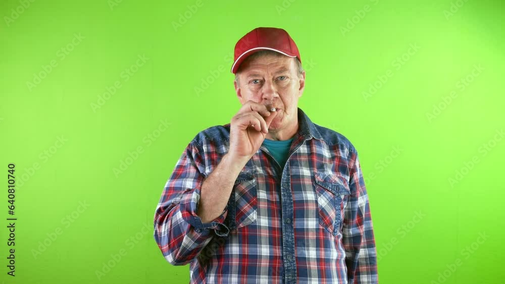 Old man in red baseball cap smoking cigarette and looking at camera. Old man in red baseball cap smoking cigarette and looking at camera.