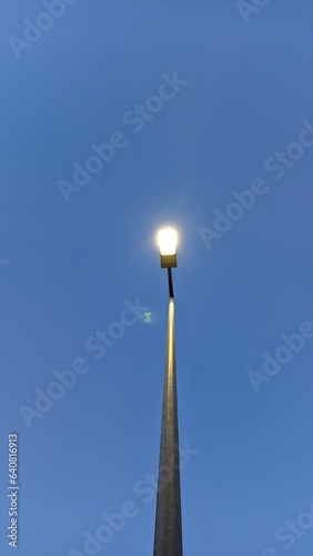 High lamppost in the evening against the blue sky photo from bottom to top