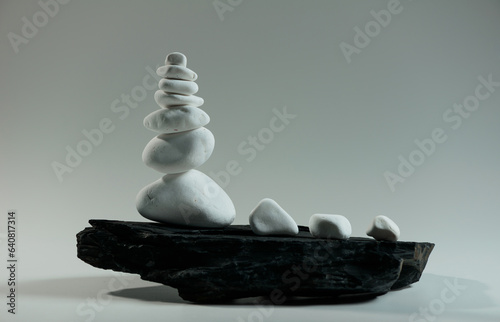 white smooth stones balanced over one black flat stone 