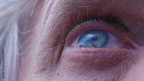 Macro close-up of a senior man's blye eyes staring at clouds in the sky. Extreme detail of person's eye ball looking at sky with HOPE photo