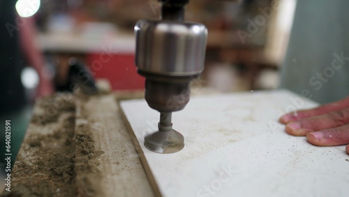 Drilling machine making a hole into a wooden surface at high-speed motion. Carpentry equipment detail close-up