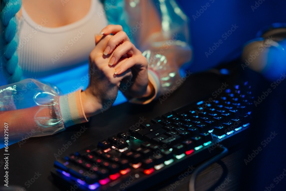Young female blogger, gamer plays games on computer. Neon computer club.