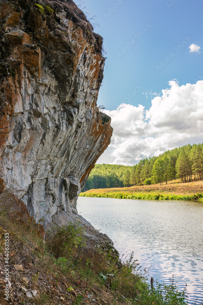 Pine trees and rocks on the river shore with fall foliage around Pine trees and rocks on the river shore with fall foliage around