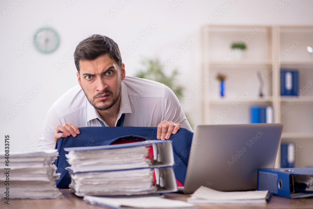 Young male employee and too much work in the office Young male employee and too much work in the office