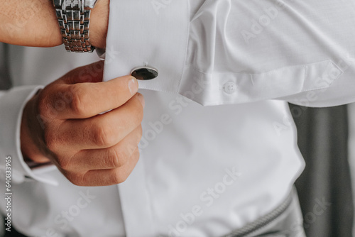 Photography Close-up of man in white shirt adjusting cufflinks