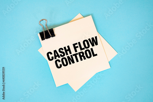 Text CASH FLOW CONTROL on sticky notes with copy space and paper clip isolated on red background.Finance and economics concept.