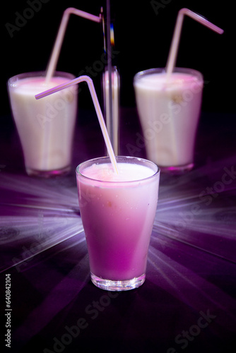 glasses with a milkshake reflected in mirrors and illuminated by colored light