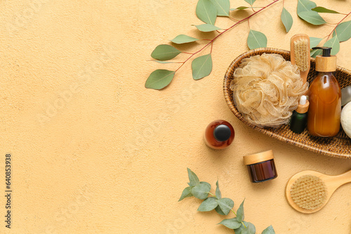 Composition with cosmetic products, bath accessories and eucalyptus branches on color background