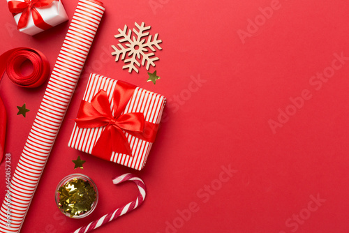 Gift boxes with paper's rools and christmas decoration on color background, top view