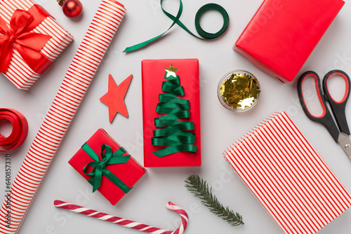 Gift boxes with paper's rools and christmas decoration on color background, top view