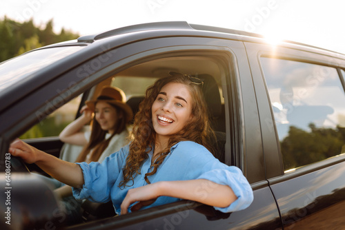 Two women travelers travel by car, have fun. Beautiful female friends in the car enjoy a car trip together. Travel, tourism. © maxbelchenko