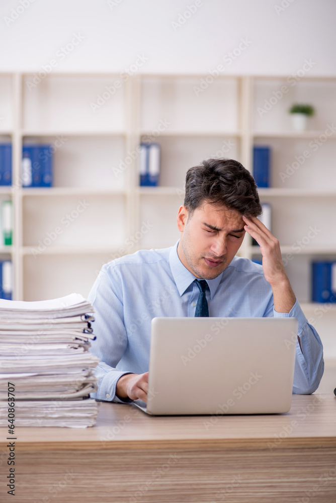 Young male employee and too much work in the office Young male employee and too much work in the office