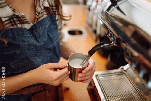 Woman bartender prepares a drink using a coffee machine in a cafe. Takeaway food.