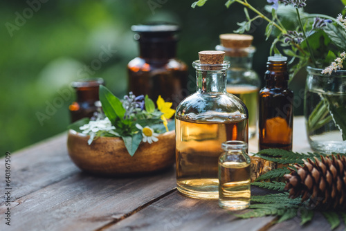Concept of alternative herbal medicine. Bottles of tincture or potion, organic essential oils, dry healthy herbs, floral extracts on wooden table. Pure natural ingredients for cosmetic production photo