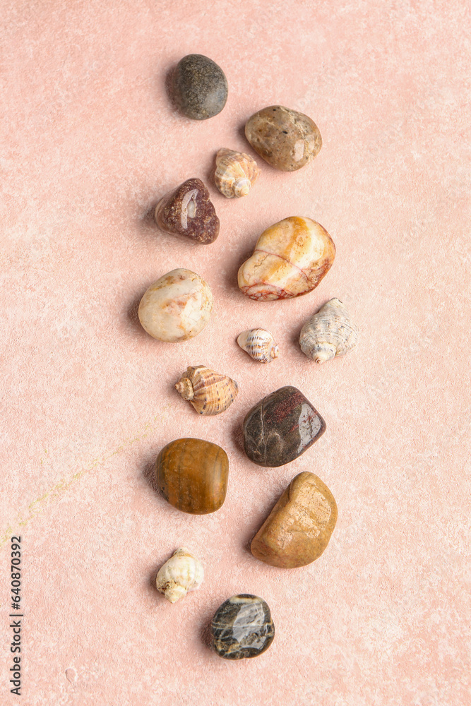 Obraz premium Many pebble stones and seashells on pink background