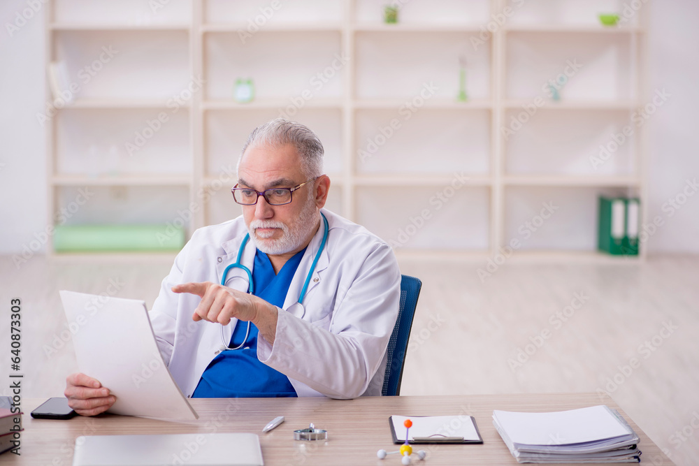 Old male doctor working in the clinic Old male doctor working in the clinic