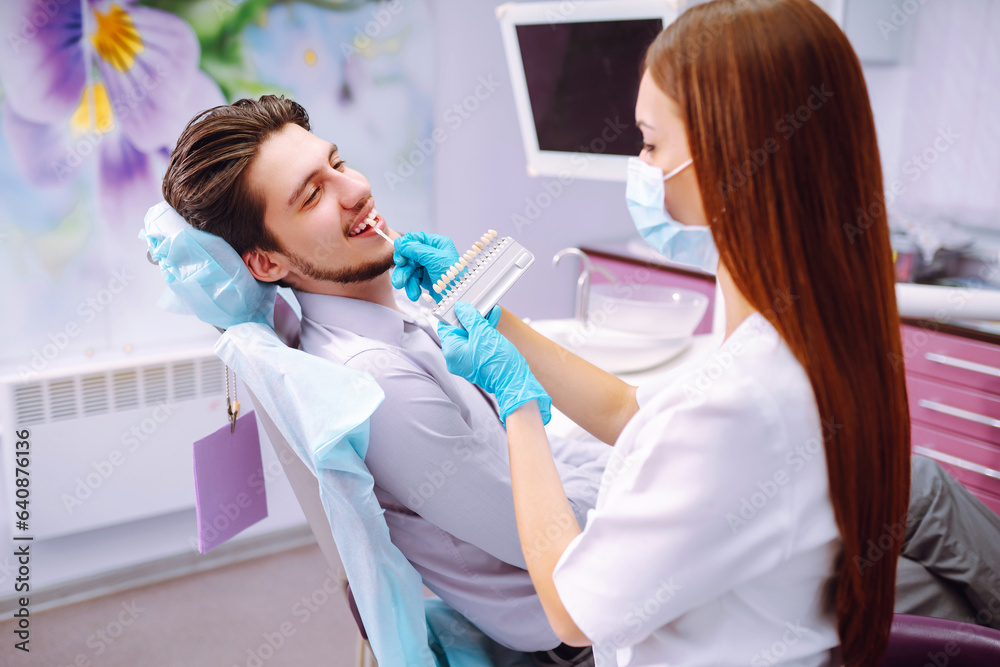 Smiling man in a dental chair during a dental procedure. The patient enjoys dental treatment at a professional dentist. Healthy smile. Dental health.
