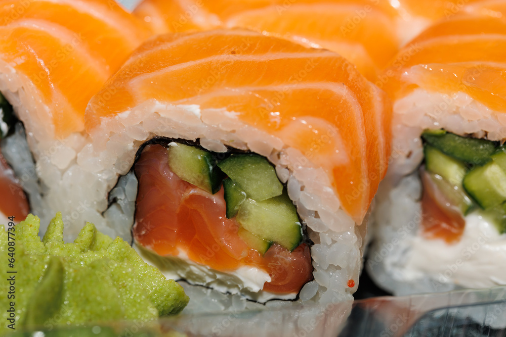 Sushi roll with salmon, avocado, smoked eel, cream cheese on a black background. Japanese food. Sushi roll with salmon, avocado, smoked eel, cream cheese on a black background. Japanese food.