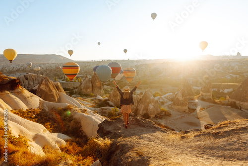 Canvas Print Woman tourist in a hat stands with her back on a mountain, looking at the balloons in Cappadocia, Turkey