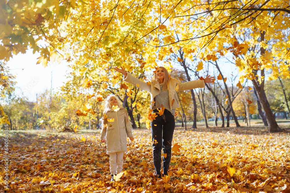 Happy young mother and daughter spend time together walking in the autumn park. Mom and child have fun outdoors in autumn. The concept of relaxation, childhood, fun. Happy young mother and daughter spend time together walking in the autumn park. Mom and child have fun outdoors in autumn. The concept of relaxation, childhood, fun.