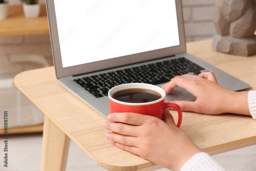 Woman with cup of coffee working on laptop at home Woman with cup of coffee working on laptop at home
